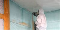 Man spraying foam insulation onto wall