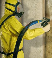 Man spraying spray foam insulation onto wall