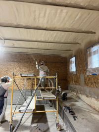 Person spraying foam insulation onto ceiling