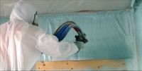 Spray foam specialist spraying a wall with blue spray foam insulation