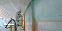 Man spraying blue foam insulation onto walls